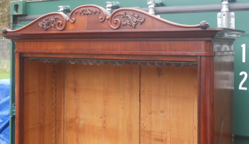 A tall Victorian mahogany open bookcase featuring a carved scroll cresting, adjustable internal shelves, and pine-panelled backing. View V