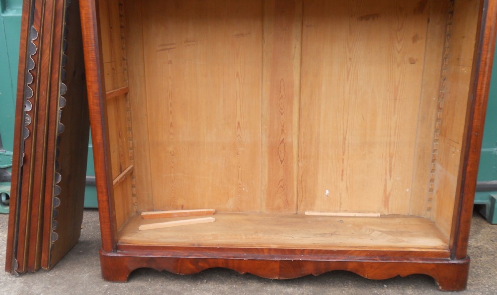 A tall Victorian mahogany open bookcase featuring a carved scroll cresting, adjustable internal shelves, and pine-panelled backing. View VI