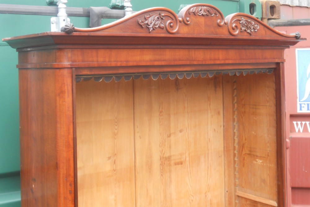 A tall Victorian mahogany open bookcase featuring a carved scroll cresting, adjustable internal shelves, and pine-panelled backing. View X