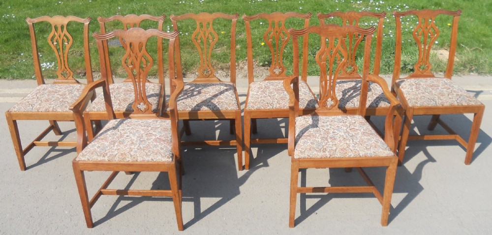 A set of eight warm brown oak Chippendale style dining chairs, comprising six side chairs and two carvers with patterned fabric drop-in seats.