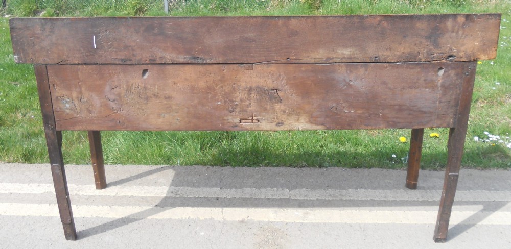 A Georgian oak dresser base with two wide drawers, brass swan-neck handles, keyhole escutcheons, a scalloped apron, and a wooden backboard. View XIV