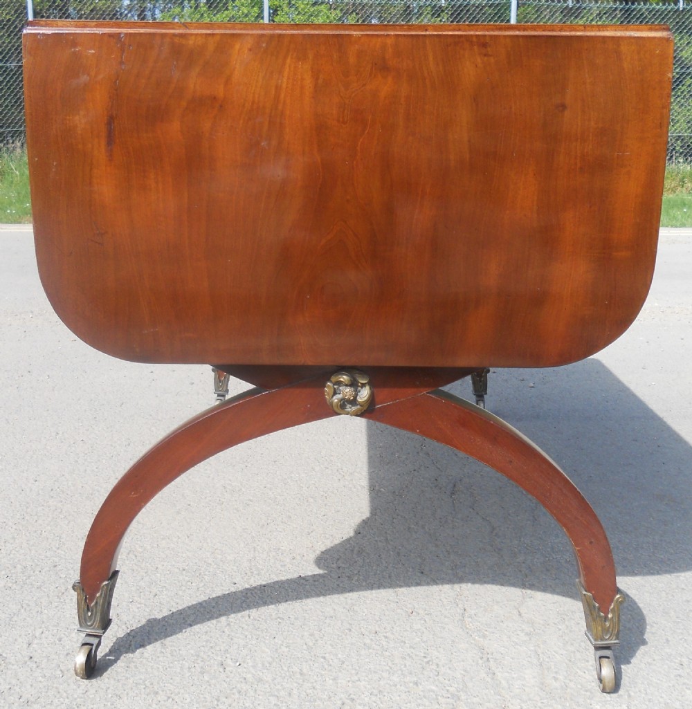 A Regency mahogany sofa table with two drop-leaf ends, twin drawers, turned stretchers, and curved sabre legs on brass castors. View VIII
