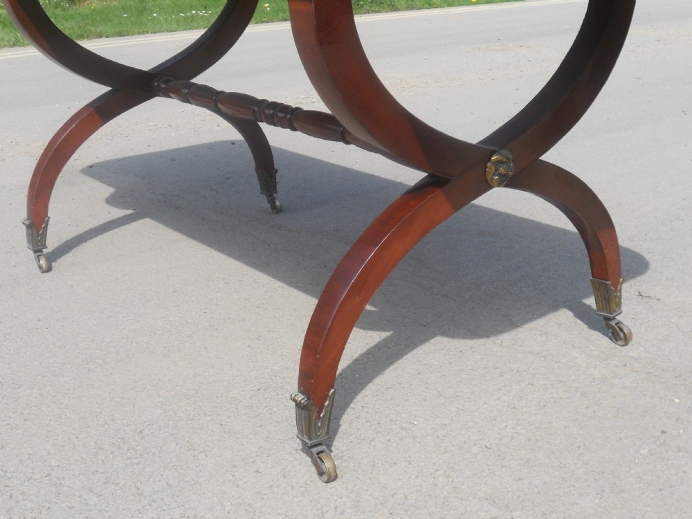 A Regency mahogany sofa table with two drop-leaf ends, twin drawers, turned stretchers, and curved sabre legs on brass castors. View X