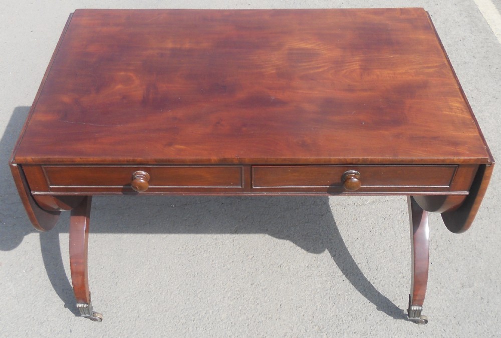 A Regency mahogany sofa table with two drop-leaf ends, twin drawers, turned stretchers, and curved sabre legs on brass castors. View XIV