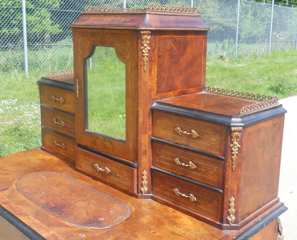 A Victorian inlaid walnut ladies writing desk featuring cabriole legs with brass mounts, small upper drawers, a central mirrored cupboard, and a leather writing inset. View IV