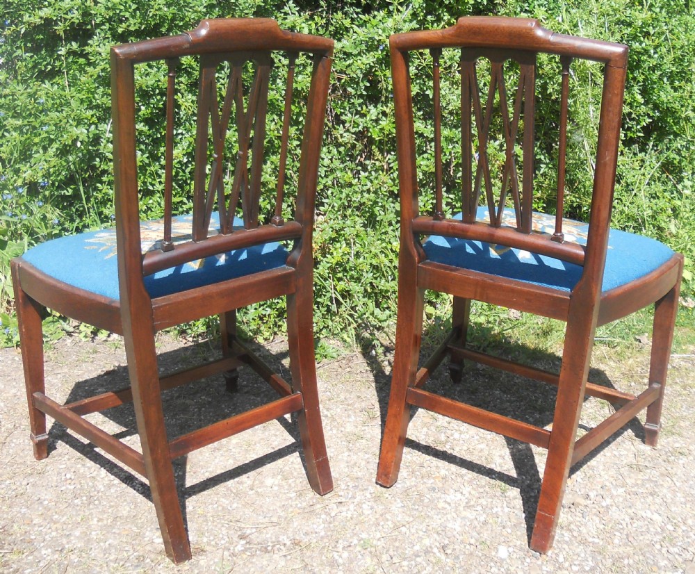 A pair of Georgian mahogany dining chairs featuring carved lattice backrests and blue needlepoint seats embroidered with floral motifs. View VII