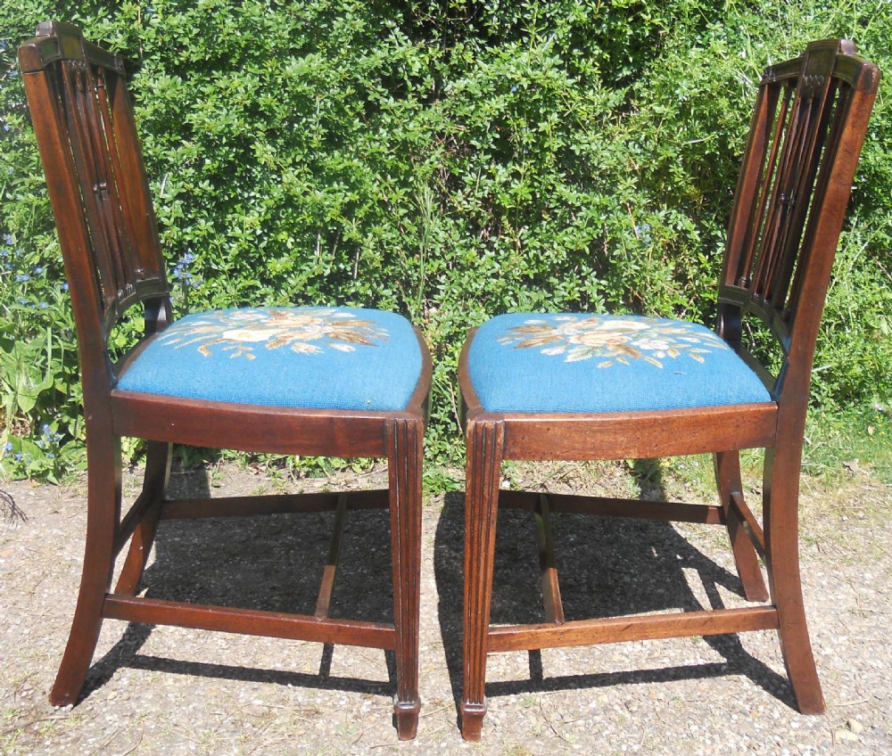 A pair of Georgian mahogany dining chairs featuring carved lattice backrests and blue needlepoint seats embroidered with floral motifs. View VIII