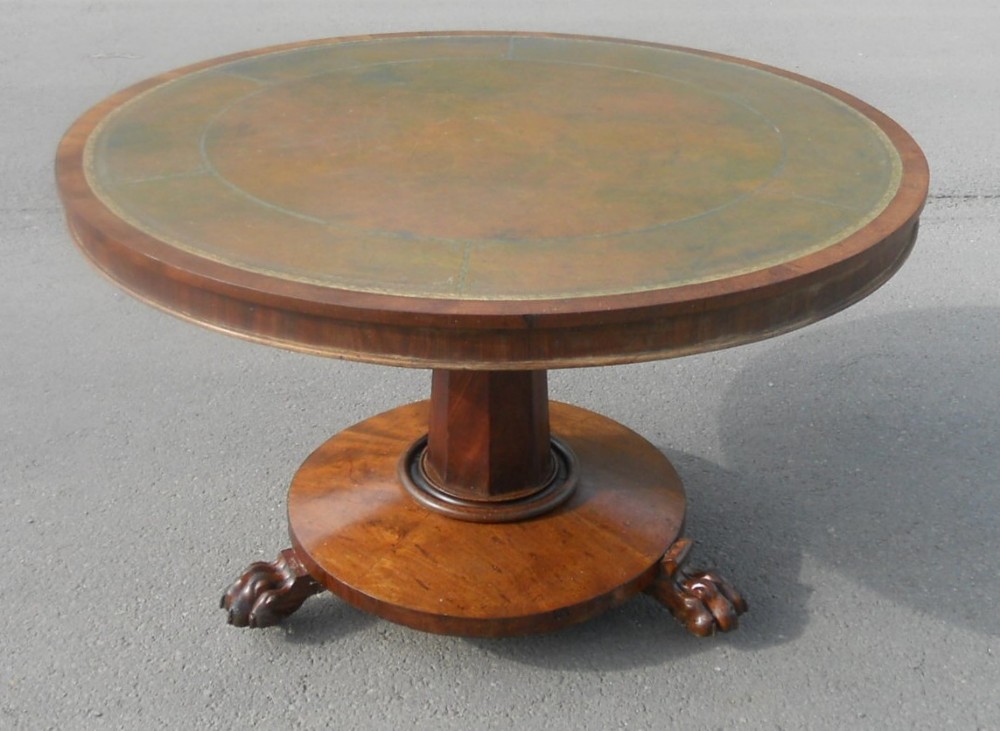 A circular Victorian mahogany centre table featuring an inset leather top, a central octagonal column pedestal, and a circular plinth base supported by carved paw feet.