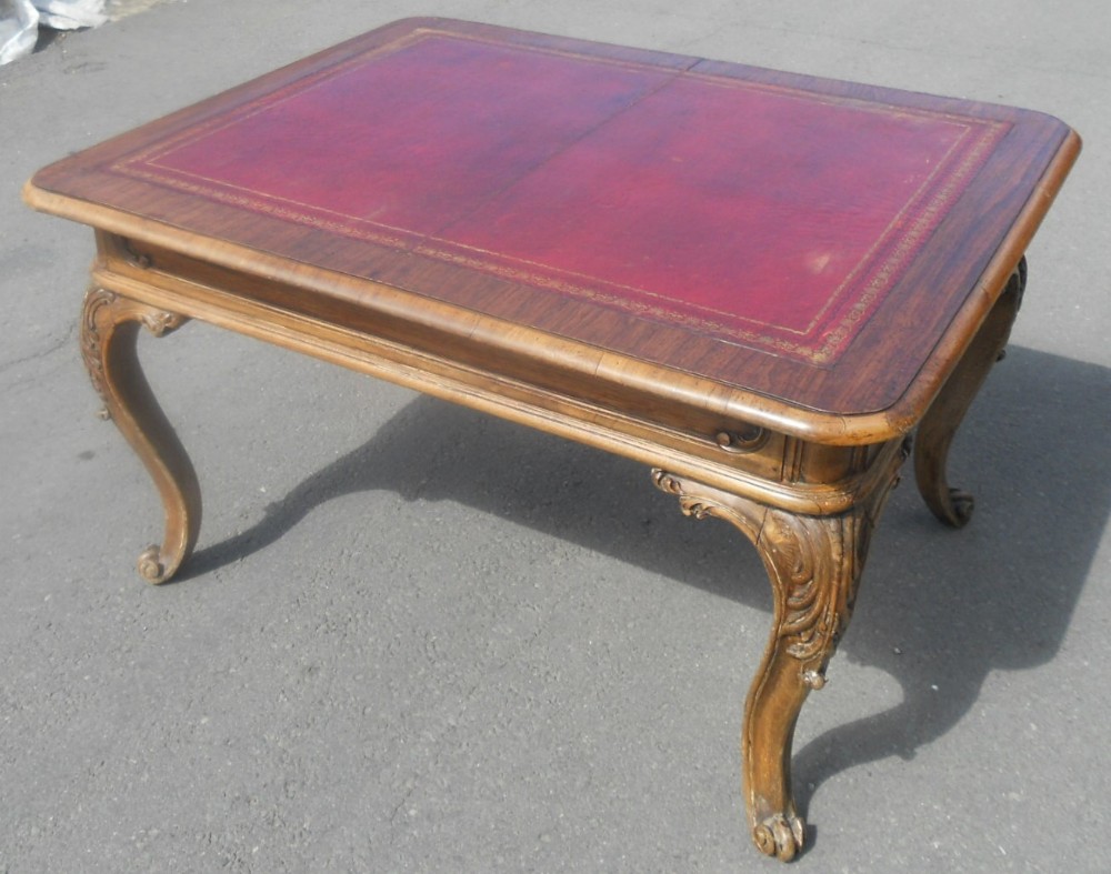 A Victorian walnut low centre table featuring a red gold-tooled leather inset top and hand-carved cabriole legs.