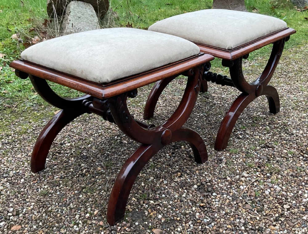 A pair of William IV mahogany x-frame stools with neutral light beige upholstered padded tops and turned central stretchers. View IV