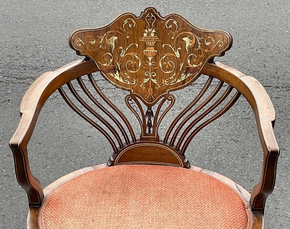 An Edwardian mahogany salon armchair featuring ornate floral and urn marquetry inlays, curved swept arms, cabriole front legs, and an upholstered circular seat. View II