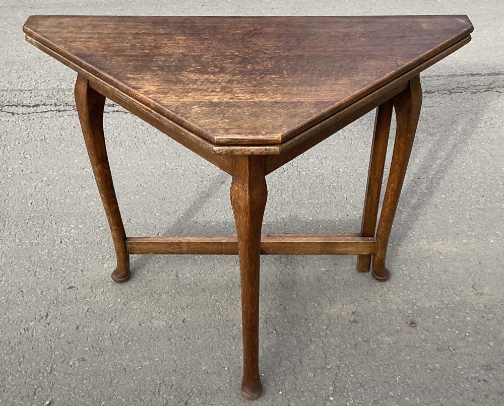 Triangular solid oak folding card table with three shaped legs and lower support stretchers. View III