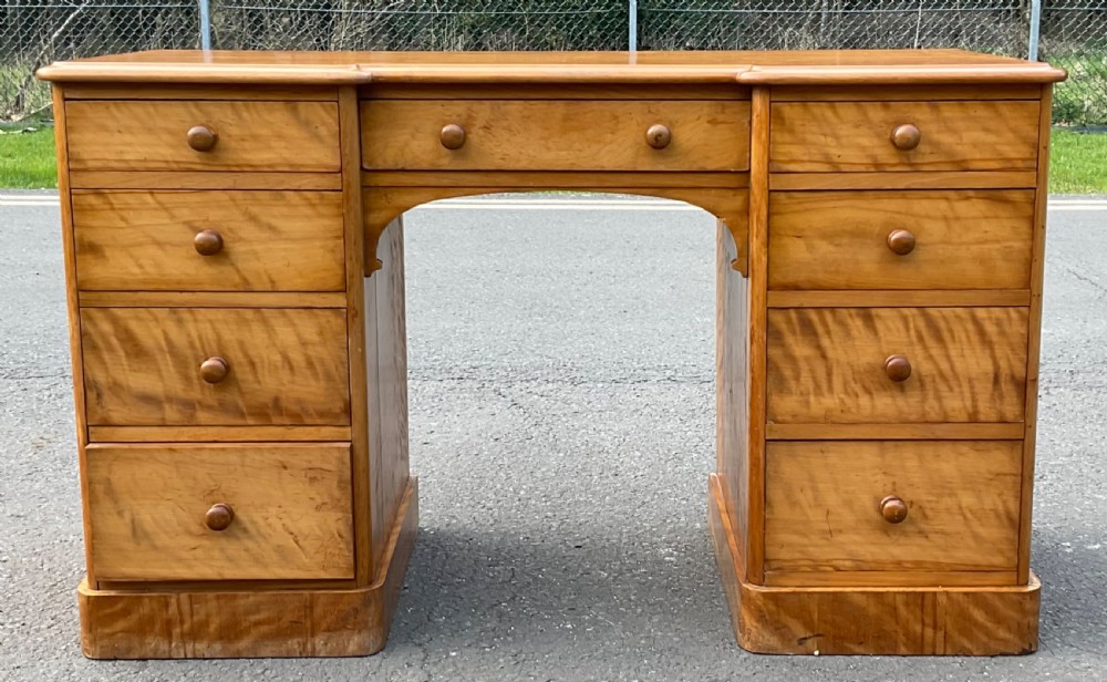 A Victorian satin birch twin-pedestal writing desk featuring nine drawers with turned timber knobs, a central arched kneehole, and plinth bases. View III