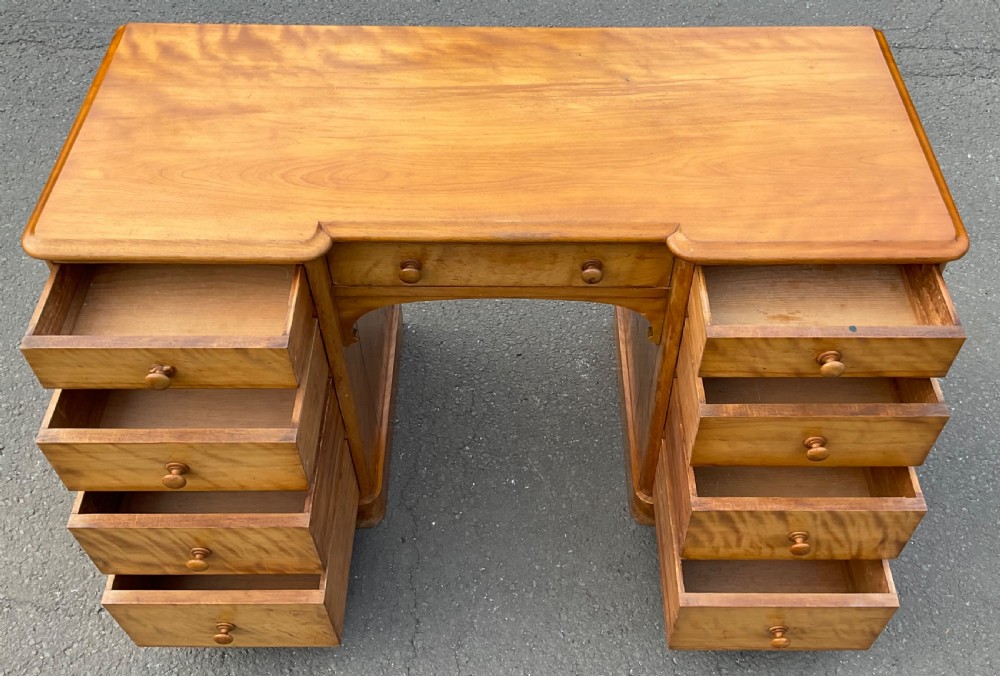 A Victorian satin birch twin-pedestal writing desk featuring nine drawers with turned timber knobs, a central arched kneehole, and plinth bases. View VII