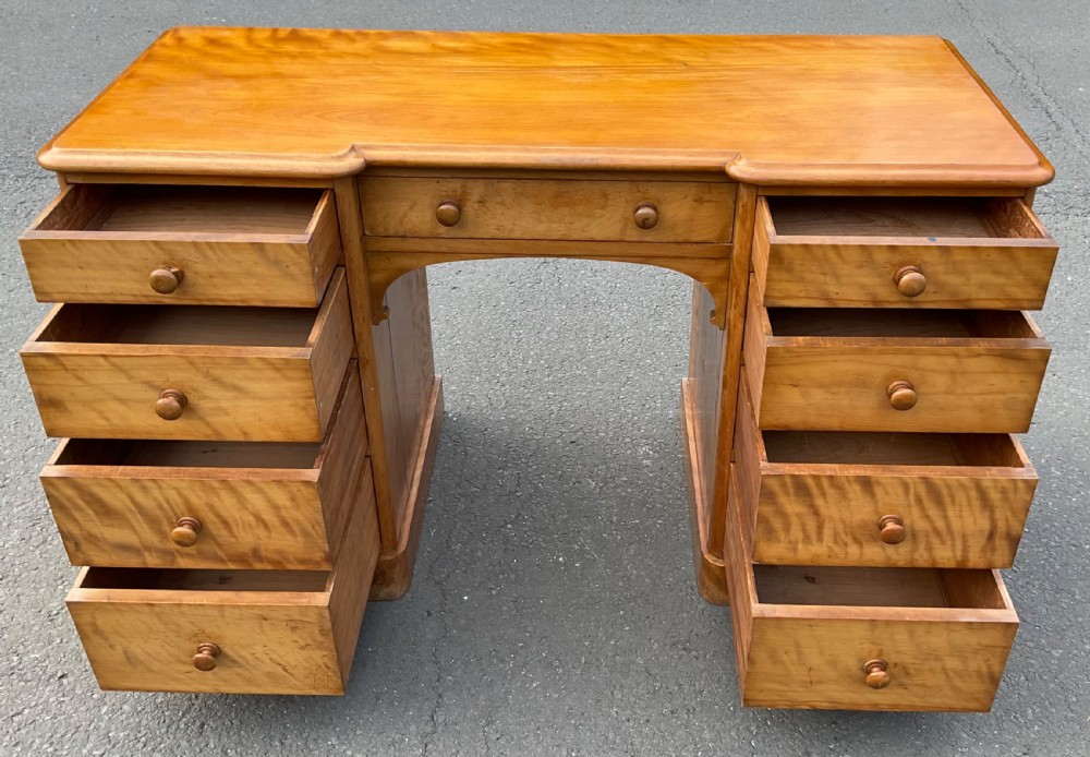 A Victorian satin birch twin-pedestal writing desk featuring nine drawers with turned timber knobs, a central arched kneehole, and plinth bases. View VIII