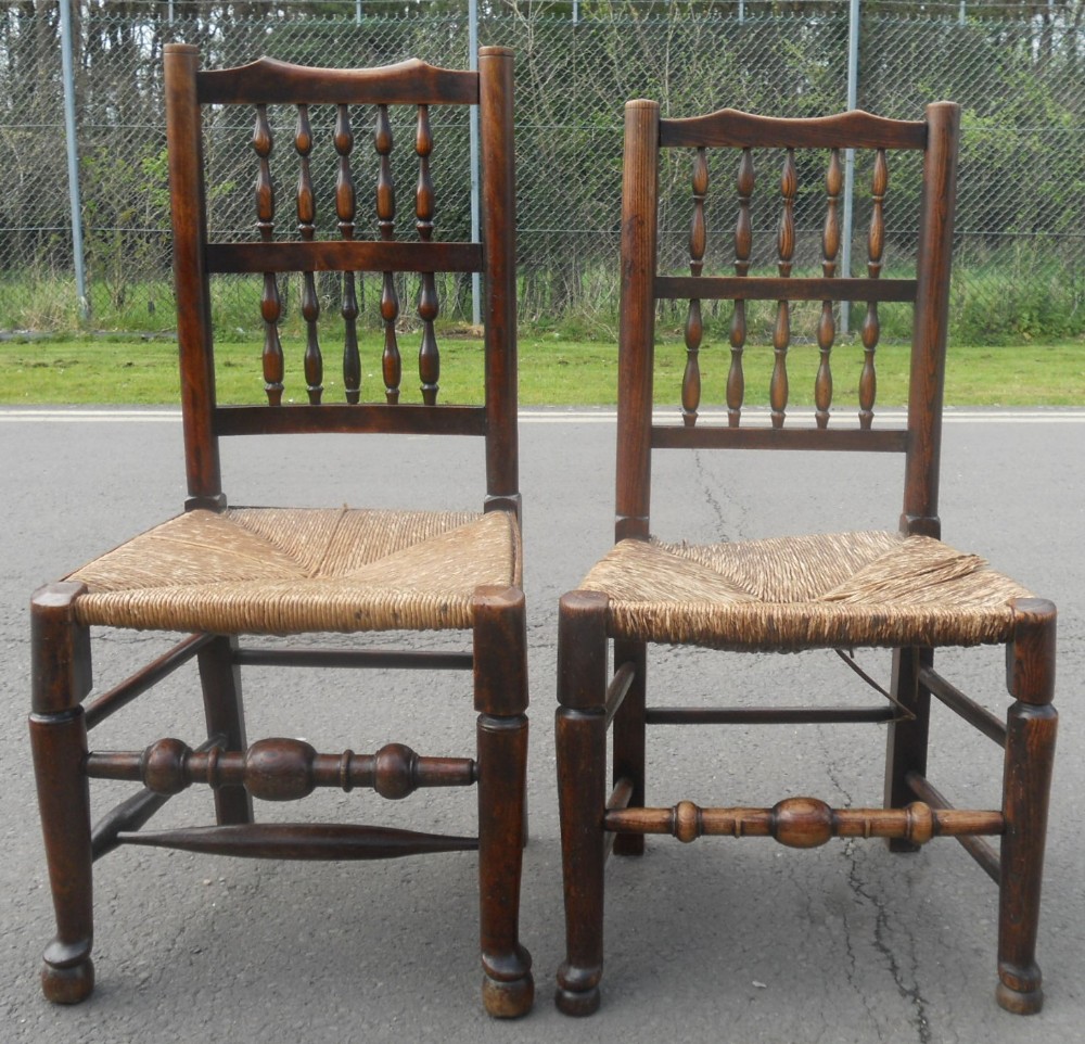 A pair of dark elm side chairs featuring double-tiered turned spindle backrests, turned front stretchers, and woven rush seats.