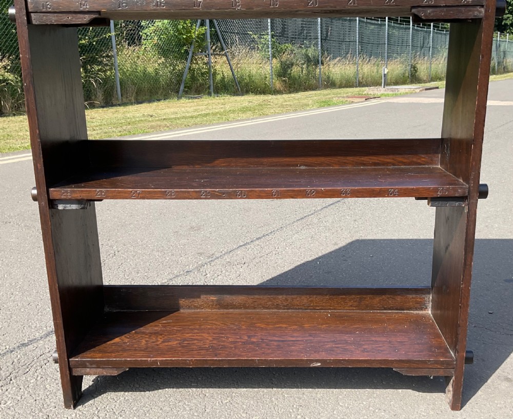 An Arts and Crafts dark oak open bookcase featuring four tier shelves and exposed peg joinery along the sides. View VI