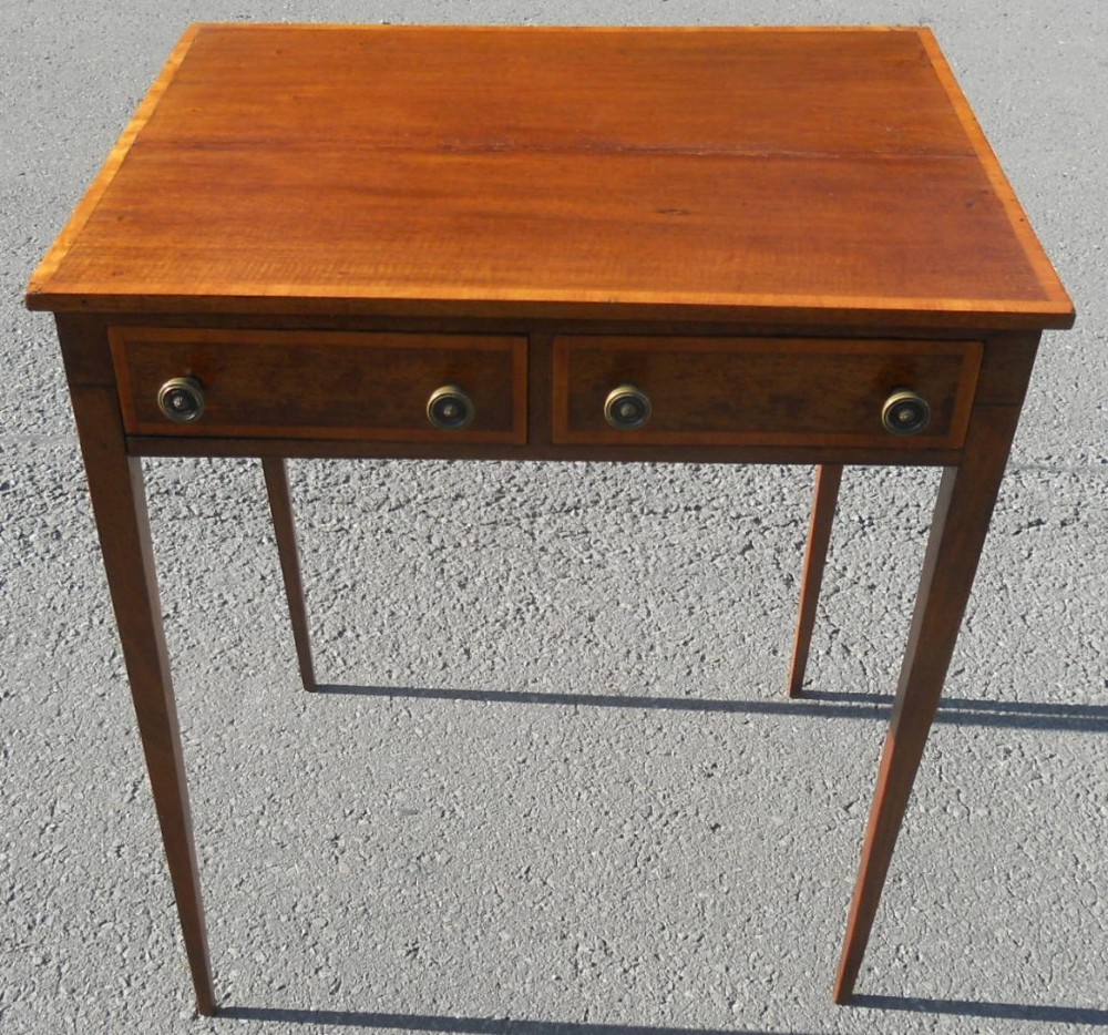 An Edwardian mahogany writing table featuring two frieze drawers with brass handles, satinwood crossbanded borders, and four square tapered legs.