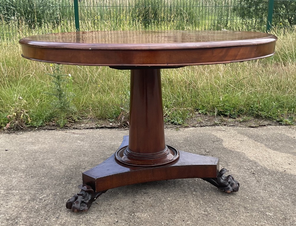 A Victorian mahogany circular centre table featuring a turned central column, a triform base, and hand-carved paw feet.