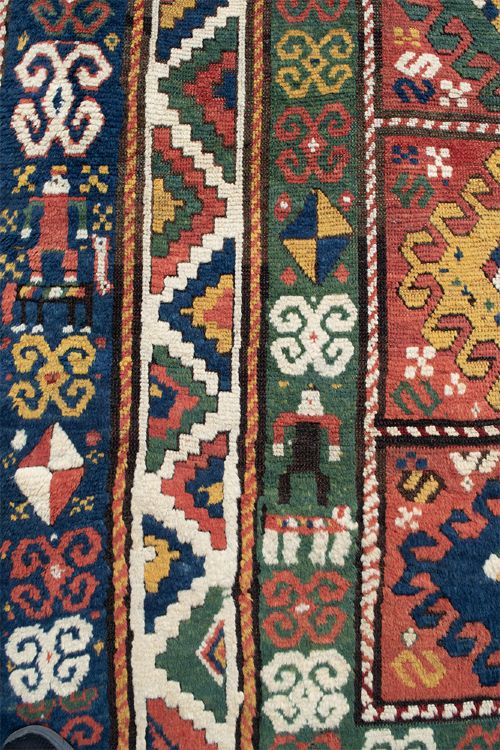 An antique Borchalu Kazak wool rug featuring stacked central diamond medallions surrounded by geometric borders in red, blue, green, and cream. View IV