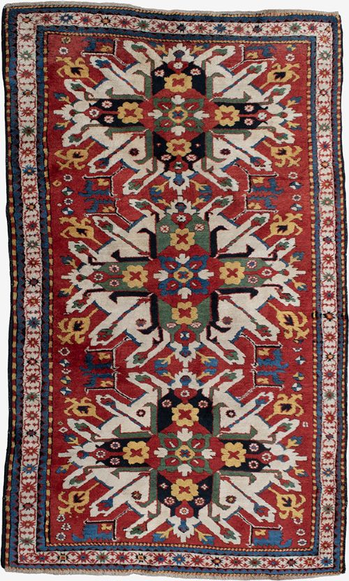 An antique hand-knotted Caucasian Eagle Kazak wool rug featuring repeating ivory geometric eagle medallions on a vibrant red field with a patterned border. View II