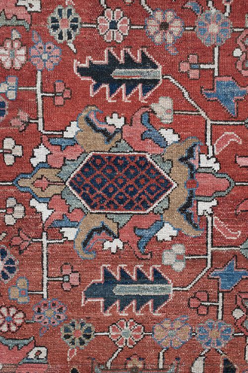 An antique Persian Heriz wool carpet featuring a central geometric medallion on a terracotta field surrounded by a dark navy decorative border. View V