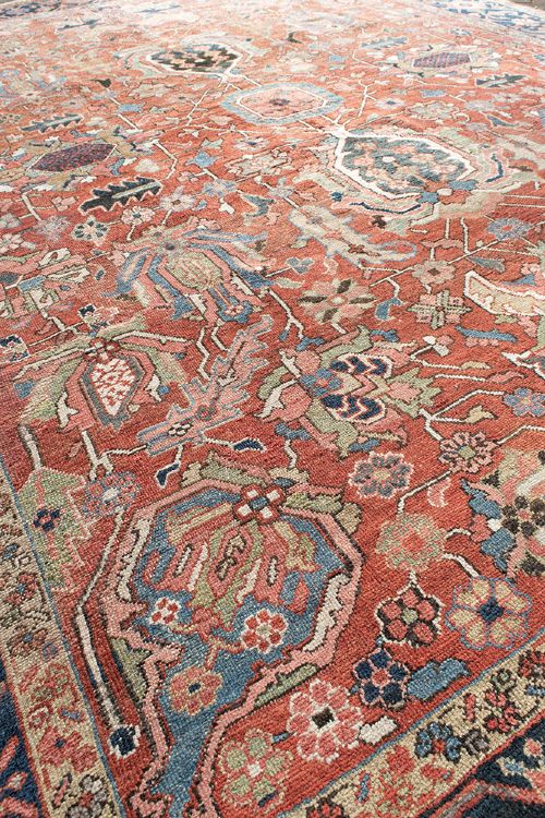 An antique Persian Heriz wool carpet featuring a central geometric medallion on a terracotta field surrounded by a dark navy decorative border. View VIII