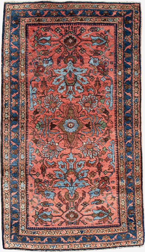 A small rectangular hand-knotted wool rug featuring a coral-red central field decorated with blue and brown floral motifs surrounded by a dark blue border. View II