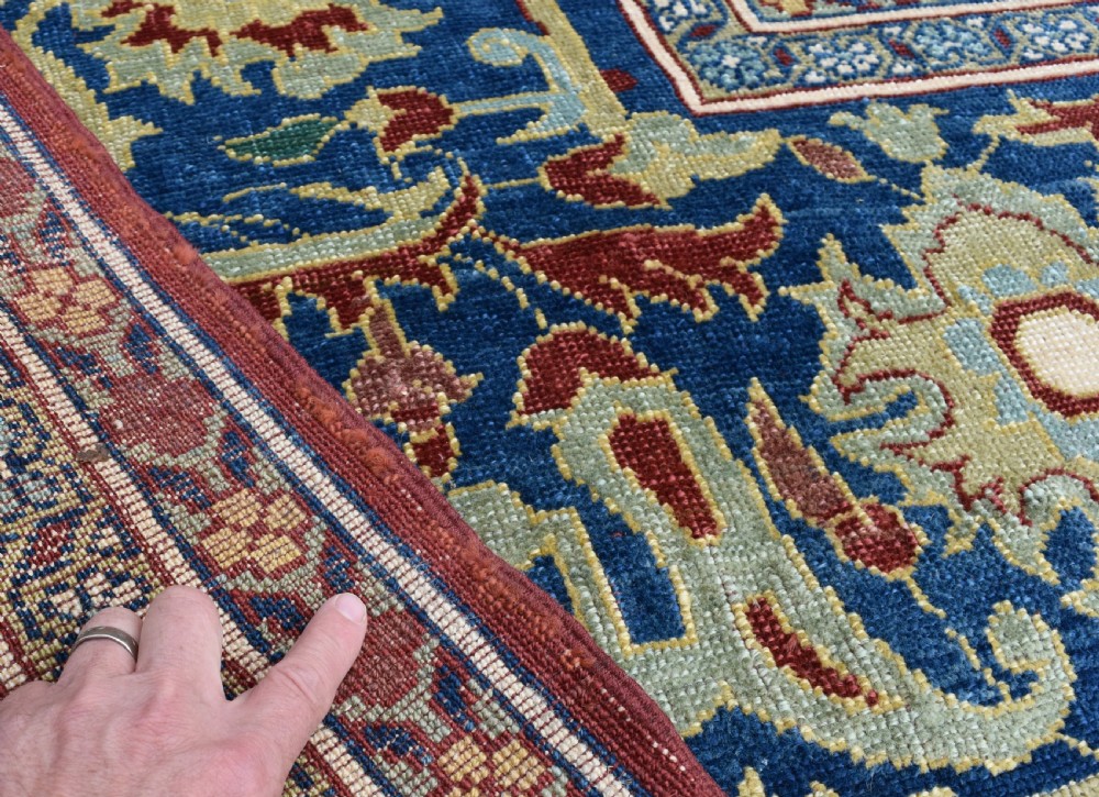 A large hand-knotted Persian wool carpet featuring a terracotta ground decorated with elaborate blue and ivory floral arabesques framed by an indigo border. View II