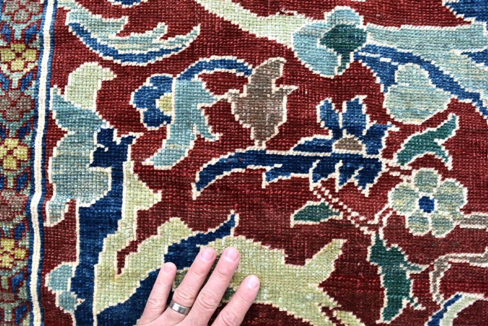 A large hand-knotted Persian wool carpet featuring a terracotta ground decorated with elaborate blue and ivory floral arabesques framed by an indigo border. View V