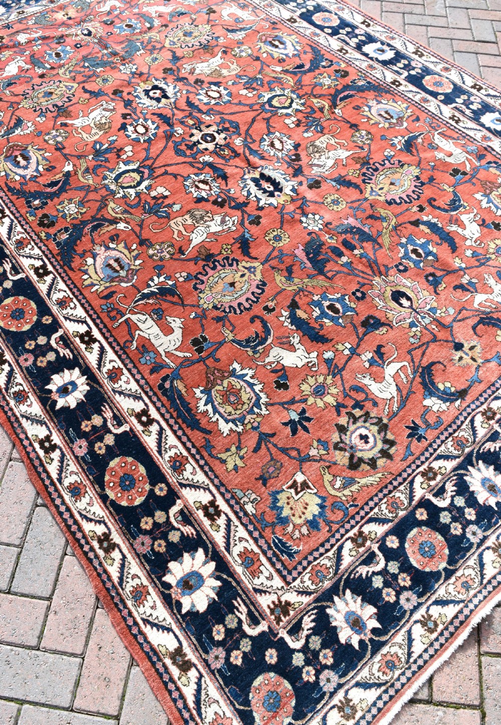 A large hand-knotted antique Persian Veramin carpet featuring animal and floral motifs on a terracotta field with a dark navy border. View VI