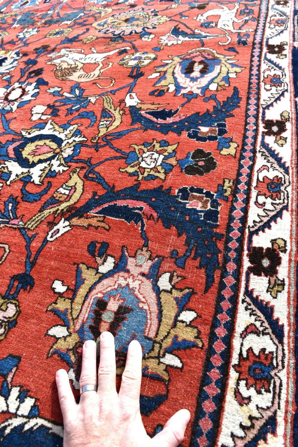 A large hand-knotted antique Persian Veramin carpet featuring animal and floral motifs on a terracotta field with a dark navy border. View VII