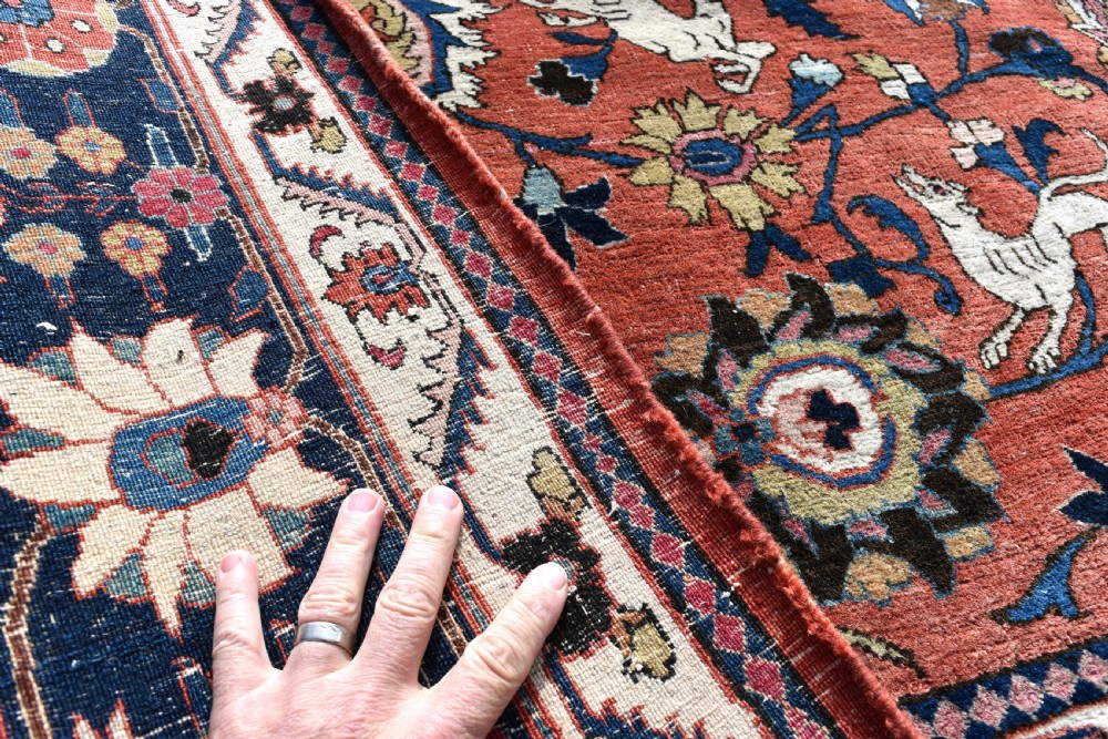 A large hand-knotted antique Persian Veramin carpet featuring animal and floral motifs on a terracotta field with a dark navy border. View VIII