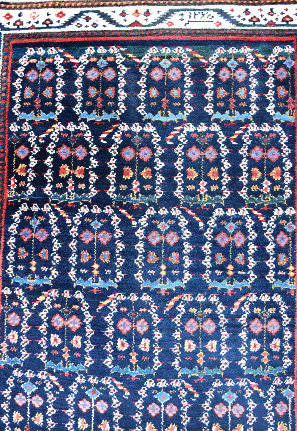 An antique Northwest Persian wool runner rug featuring repeating geometric shrub motifs on a navy blue field framed by a cream border. View II