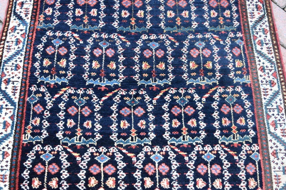 An antique Northwest Persian wool runner rug featuring repeating geometric shrub motifs on a navy blue field framed by a cream border. View IV