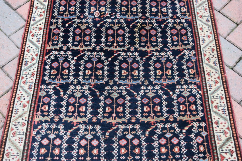 An antique Northwest Persian wool runner rug featuring repeating geometric shrub motifs on a navy blue field framed by a cream border. View VI