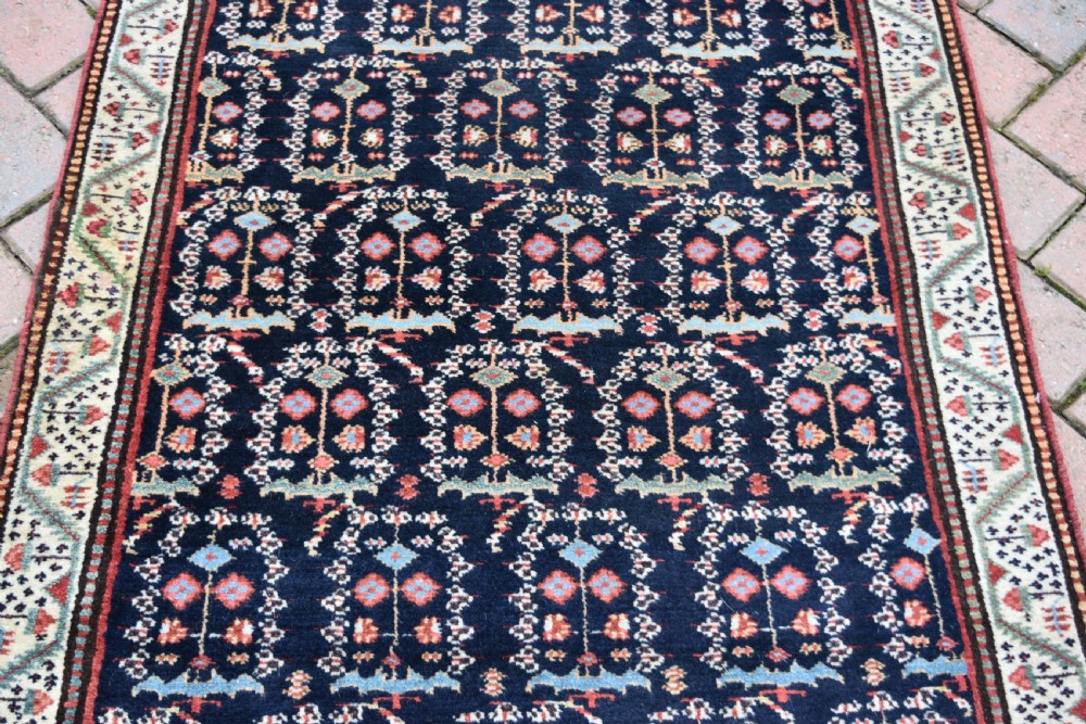An antique Northwest Persian wool runner rug featuring repeating geometric shrub motifs on a navy blue field framed by a cream border. View VII