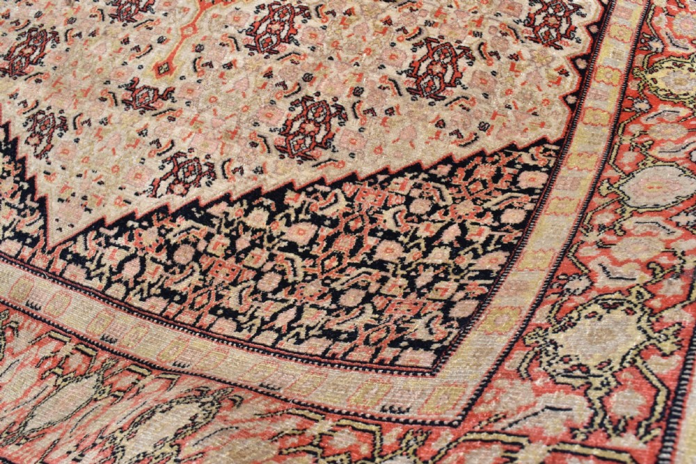An antique Persian Senneh hand-knotted wool rug featuring a central cream stepped medallion surrounded by intricate red and blue geometric borders. View V