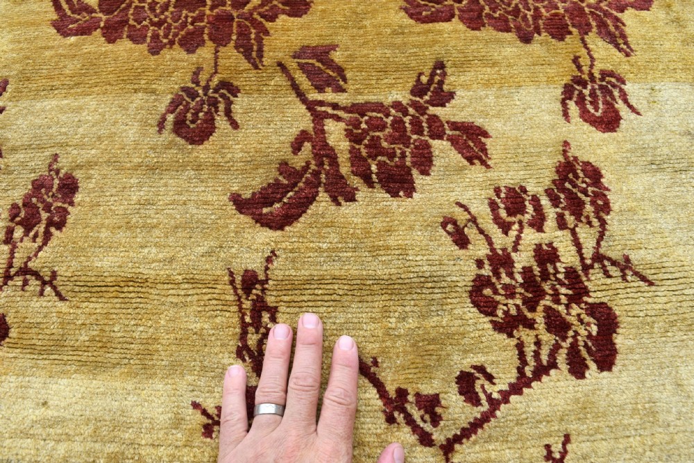 An antique rectangular Tibetan Khaden wool rug featuring a yellow field decorated with crimson floral branch motifs and fringe along the top and bottom edges. View II