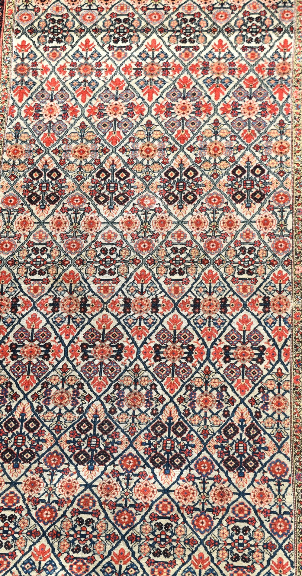 An antique long North West Persian Kelleh carpet featuring an intricate repeating lattice geometric motif in terracotta, navy blue, and cream tones. View II