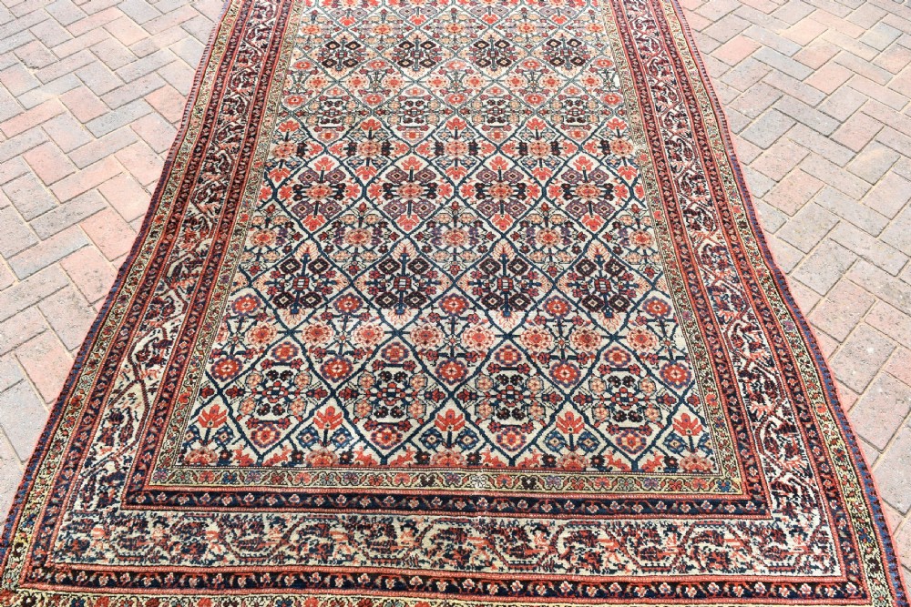 An antique long North West Persian Kelleh carpet featuring an intricate repeating lattice geometric motif in terracotta, navy blue, and cream tones. View IV