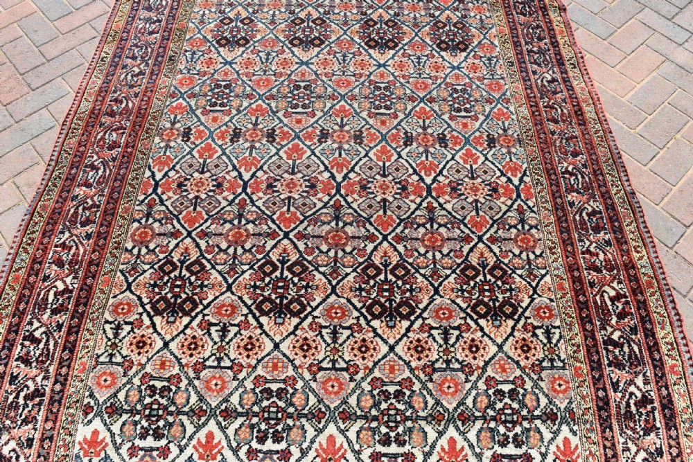 An antique long North West Persian Kelleh carpet featuring an intricate repeating lattice geometric motif in terracotta, navy blue, and cream tones. View X