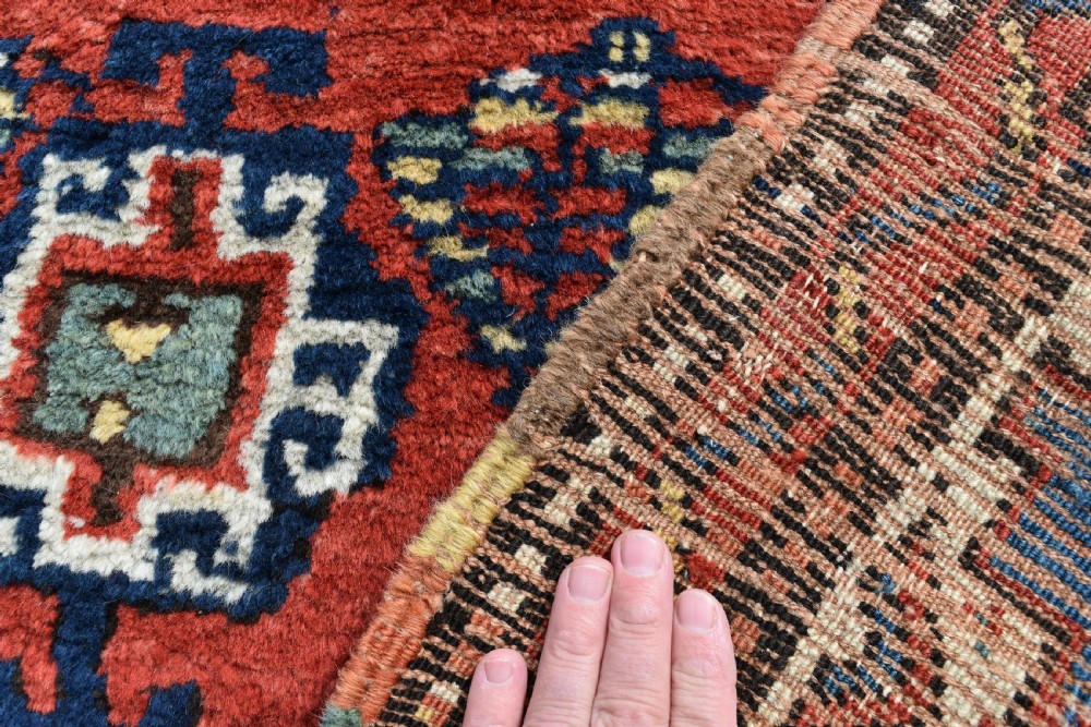 An antique Shahsavan hand-knotted wool long rug featuring geometric medallions in terracotta red, navy blue, yellow, and white. View VI