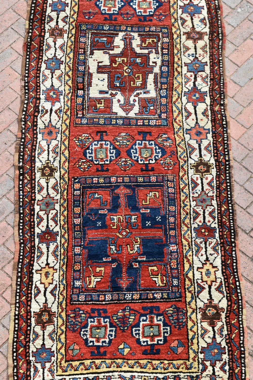 An antique Shahsavan hand-knotted wool long rug featuring geometric medallions in terracotta red, navy blue, yellow, and white. View VIII