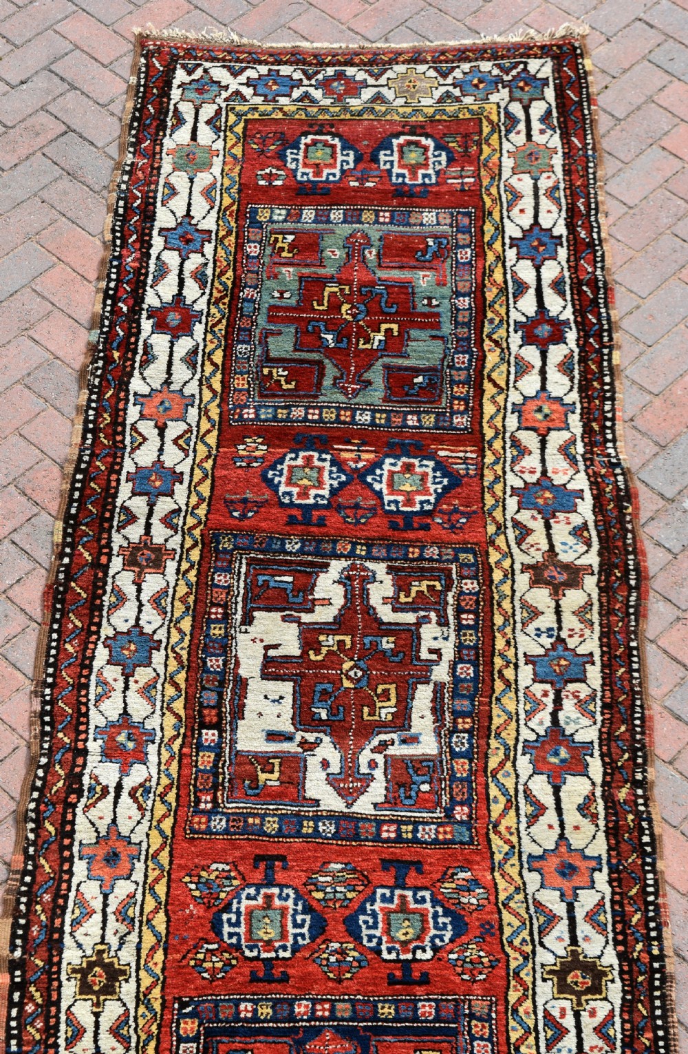 An antique Shahsavan hand-knotted wool long rug featuring geometric medallions in terracotta red, navy blue, yellow, and white. View IX
