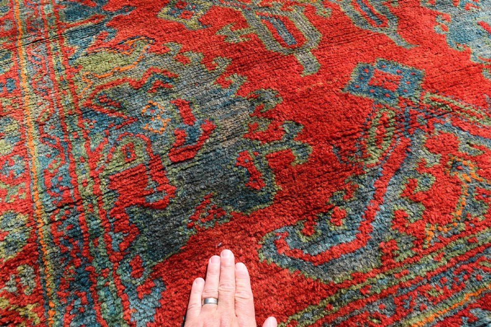 A rectangular hand-knotted antique wool Ushak carpet featuring a vibrant red field with a green and blue central medallion motif and floral borders. View IV
