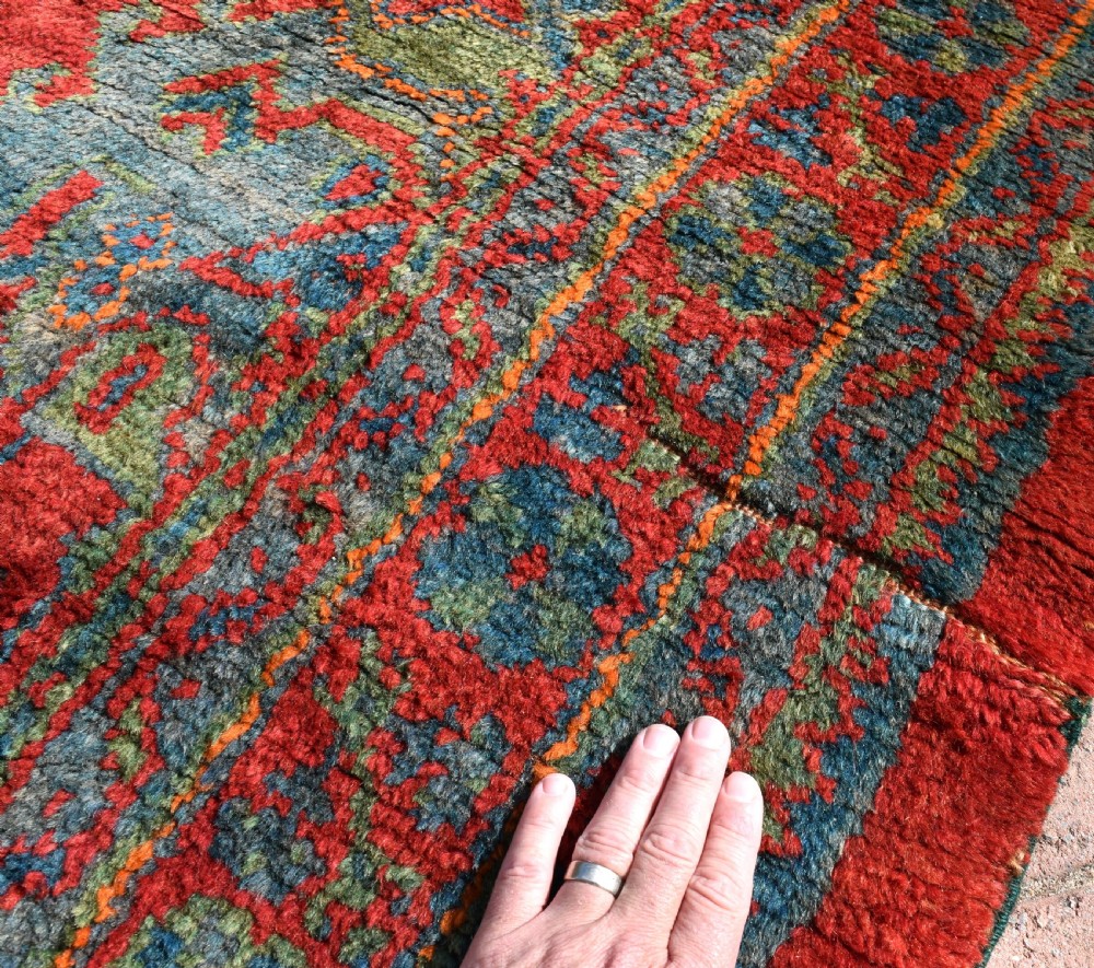 A rectangular hand-knotted antique wool Ushak carpet featuring a vibrant red field with a green and blue central medallion motif and floral borders. View VII