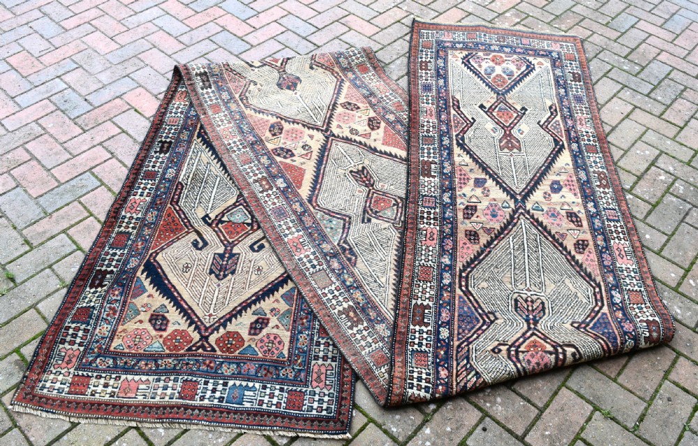A long, narrow antique hand-knotted Serab wool runner rug featuring repeating geometric diamond medallions in beige, terracotta red, pink, and navy blue tones.