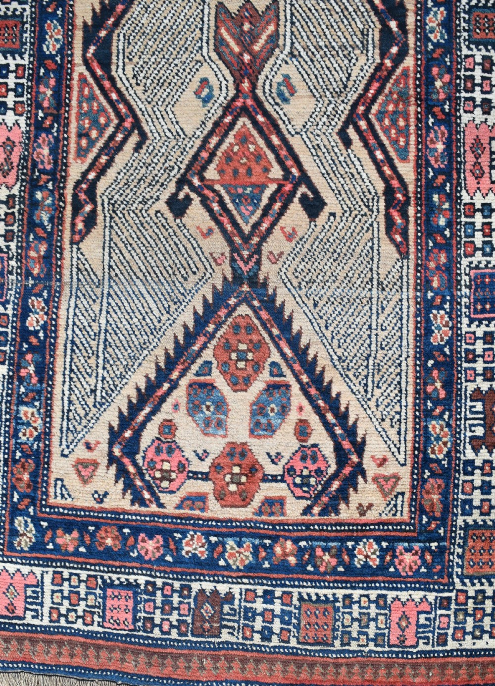 A long, narrow antique hand-knotted Serab wool runner rug featuring repeating geometric diamond medallions in beige, terracotta red, pink, and navy blue tones. View VII
