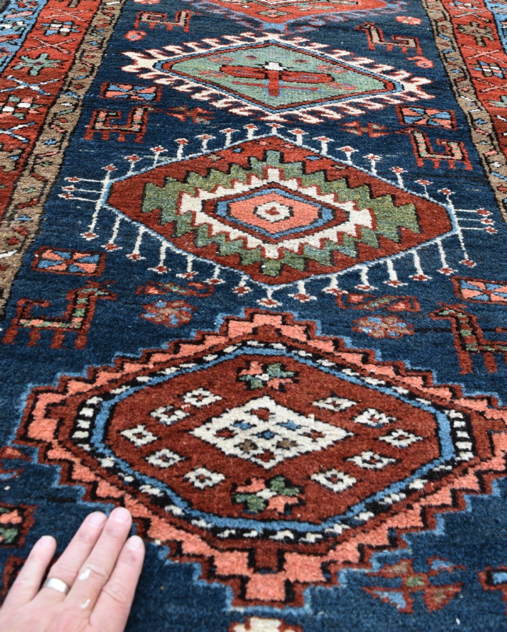 A long hand-knotted Persian Heriz runner rug featuring geometric diamond medallions on a navy blue field with terracotta red borders. View III